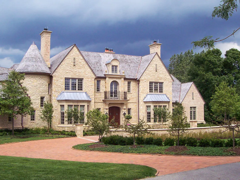 Brick paver motor court in front of a large stone home
